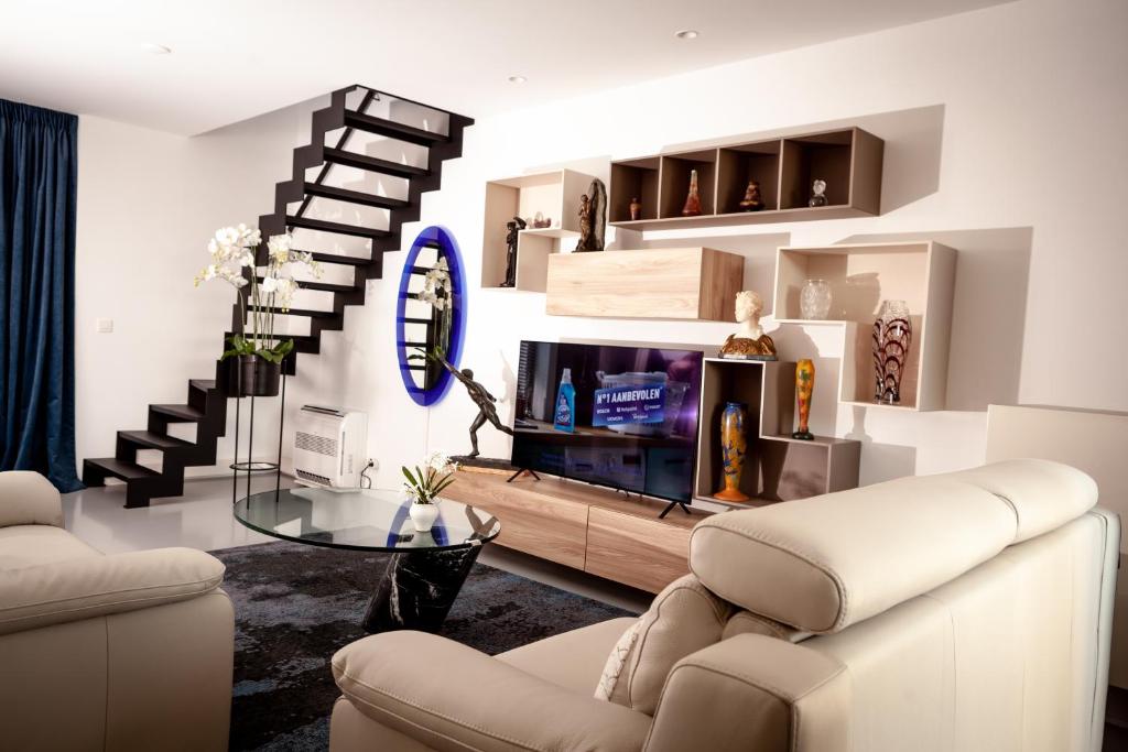 a living room with a tv and a staircase at Suite Aux Anges in Antwerp