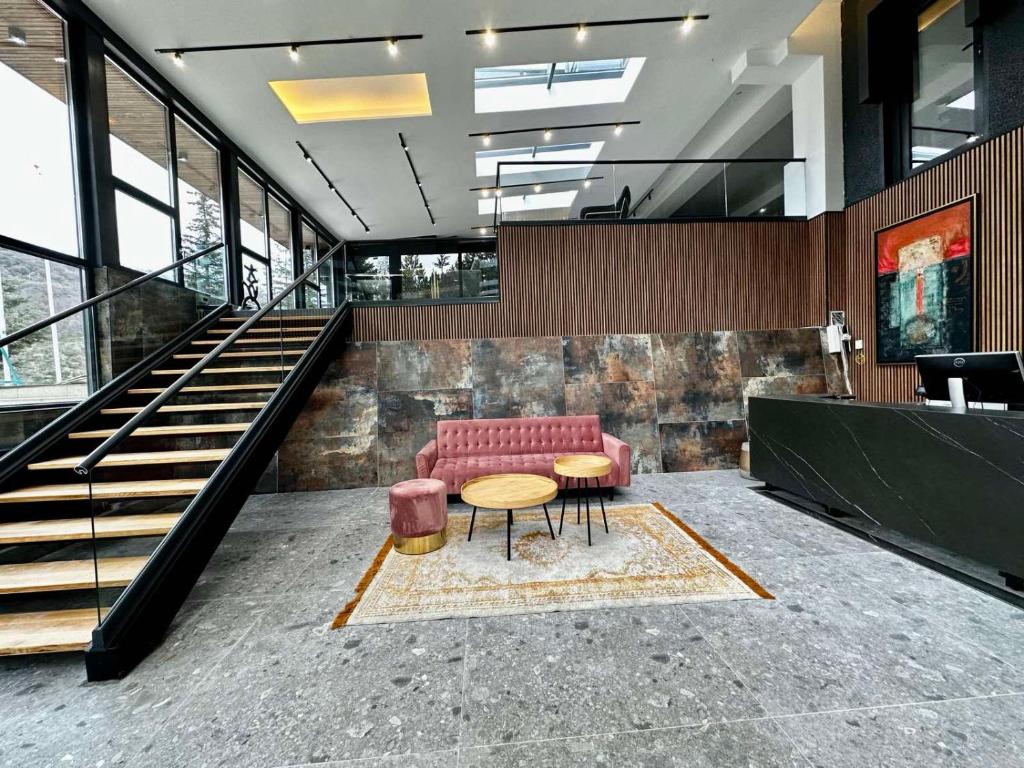 a lobby with a red couch and a table and stairs at LAKEVIEW Hotel & Apartments in Mavrovo