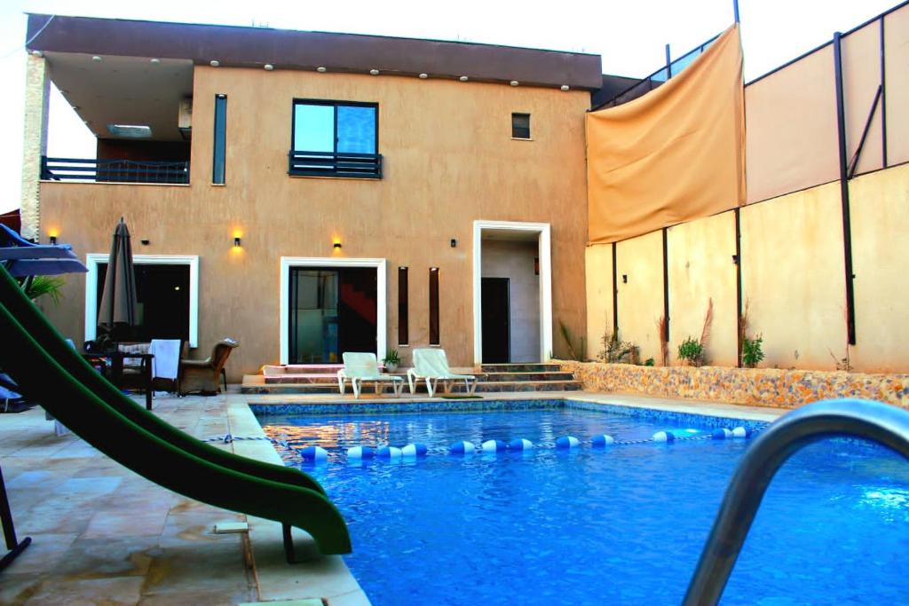 a swimming pool with a slide in front of a house at Celina's farm in Al Rama