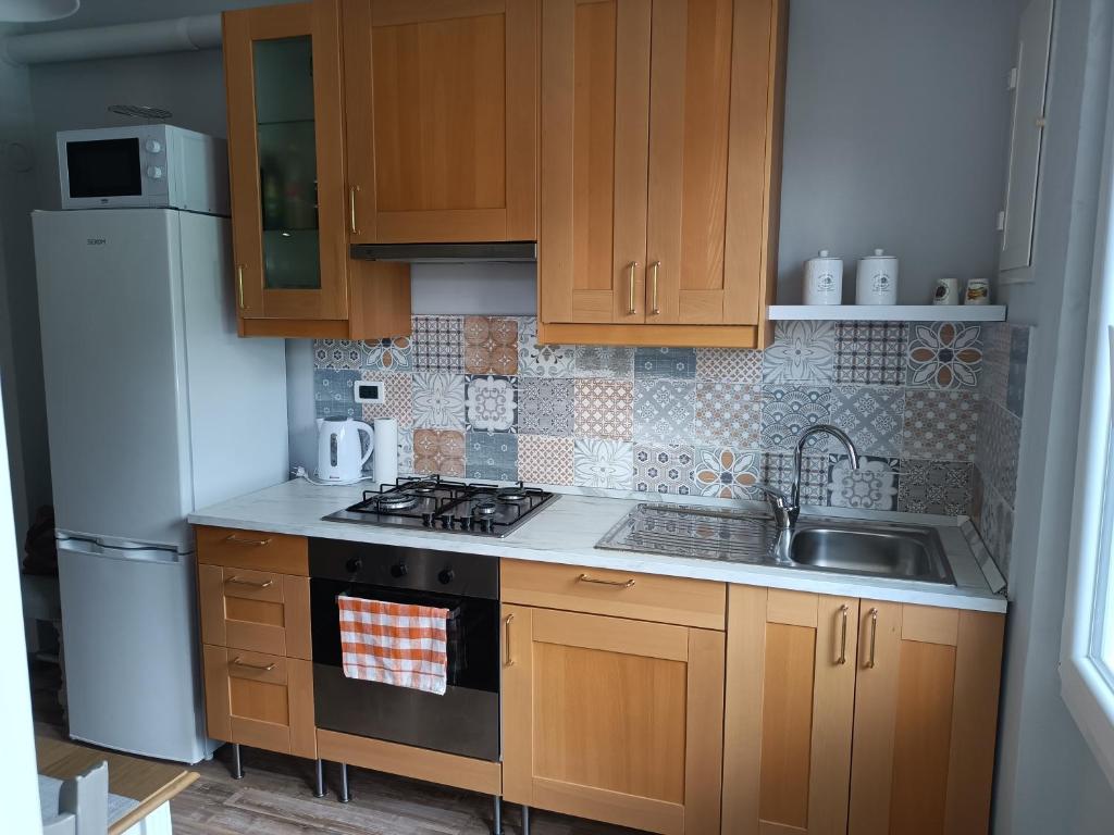 a kitchen with wooden cabinets and a sink and a refrigerator at Decò & Retrò apartment in La Spezia