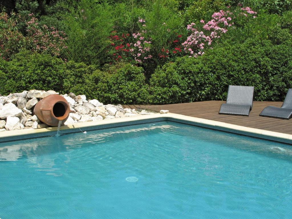 una piscina con 2 sillas y un barril en un patio en Mirabelle en Provence, en Eygalières