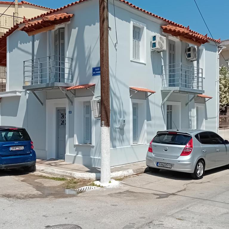 two cars parked in front of a white building at Apartments in Amarynthos - Evoia in Amarynthos