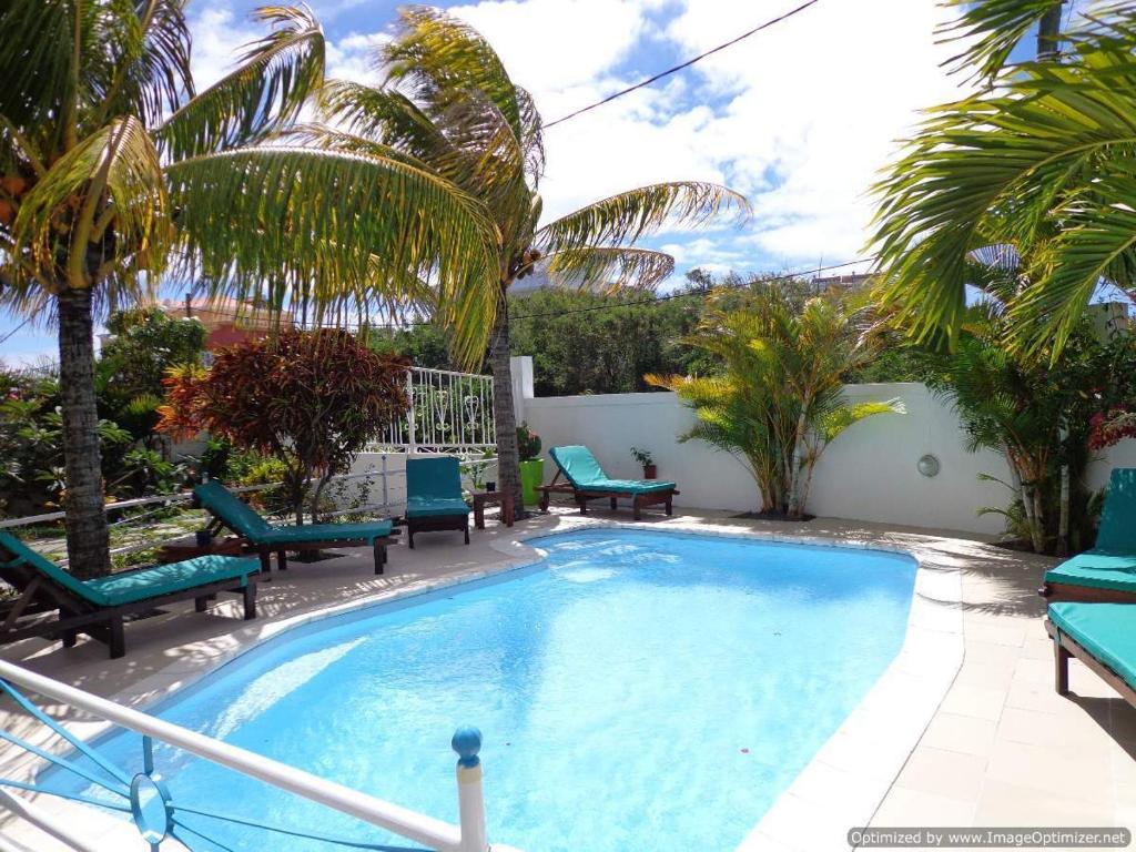 a large swimming pool with chairs and palm trees at Résidence Bleu Azur in Grand-Baie