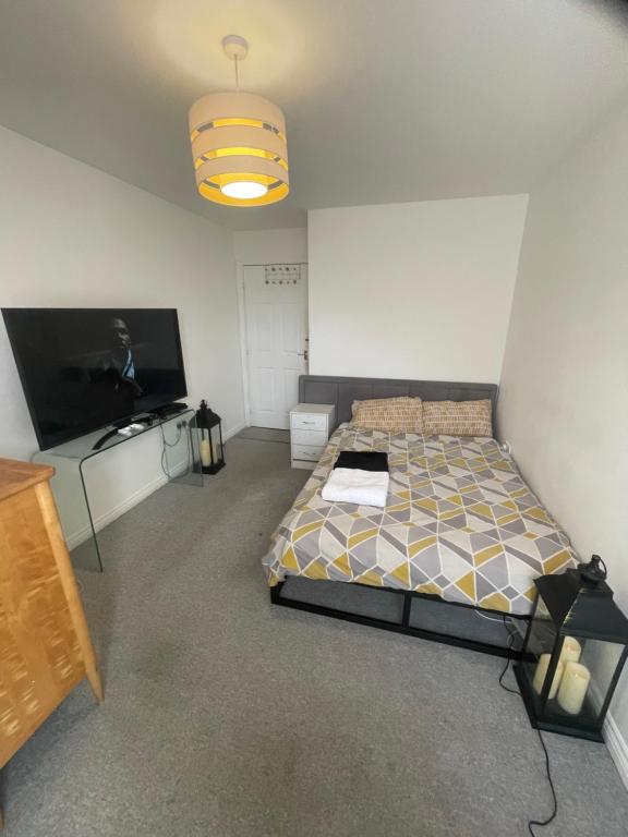 Schlafzimmer mit einem Bett und einem Flachbild-TV in der Unterkunft Rhapsody Premium in Waltham Abbey