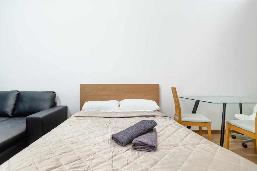 a bedroom with a bed with a couch and a table at CAMP NOU & FiRA BUSINESS LOFTS in Barcelona