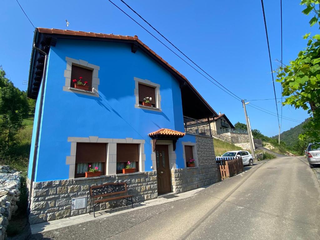 a blue house with two windows and a bench at Acogedora casa en Onís - Cangas de Onis in Avín