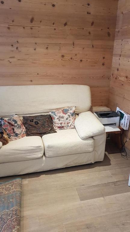 a white couch in a room with a wooden wall at Casa Gion in Santo Stefano di Cadore