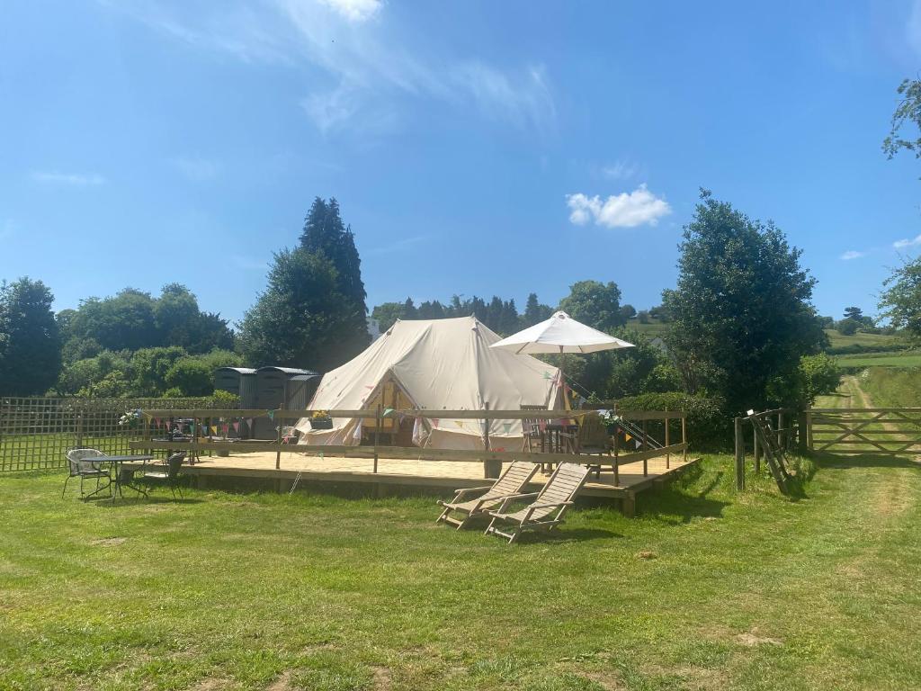 une tente avec une table et des chaises dans un champ dans l'établissement Hope Cottage Bell Tent Retreat, à Ashbourne