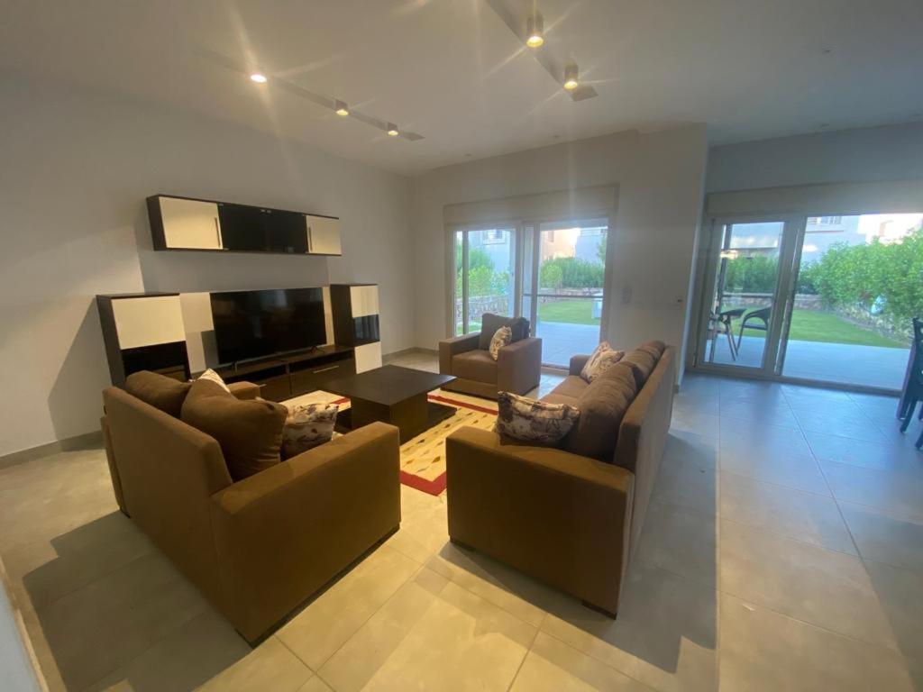 sala de estar con 2 sofás y TV de pantalla plana en Hacienda Bay Luxury Chalet هاسيندا باي en El Alamein