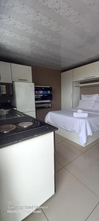 ein Schlafzimmer mit einem Bett und eine Küche mit einem Herd in der Unterkunft Dlanduna GUEST House in Umzinto