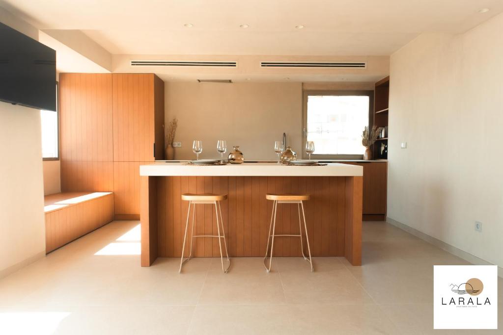 a kitchen with a counter and two stools at a kitchen island at Larala 02 - Nuevo apartamento en la playa del Arenal con vistas al mar in Jávea