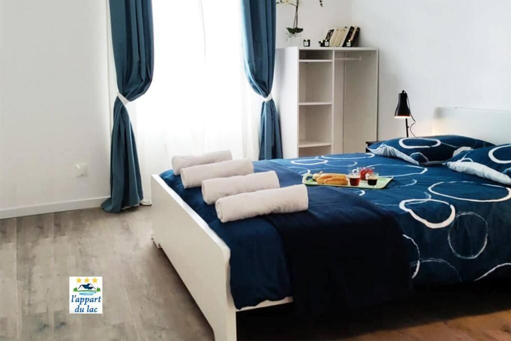 een slaapkamer met een blauw en wit bed met kussens bij L'appart du lac - Elégant et tout confort à Eguzon in Éguzon-Chantôme