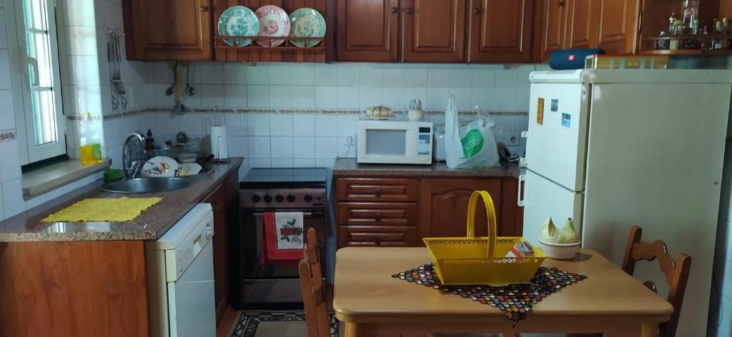 a kitchen with a table and a white refrigerator at Casa da Avó Bi in Vila Nova da Barquinha