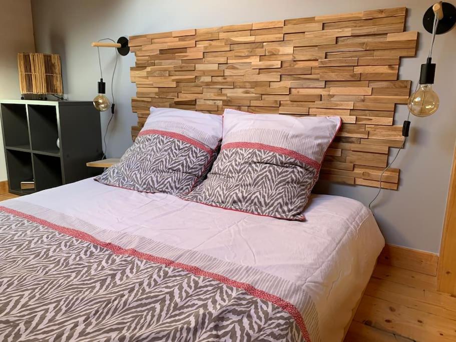 a bed with two pillows and a brick wall at Chaleureux studio plein sud en Tarentaise ! in Bozel