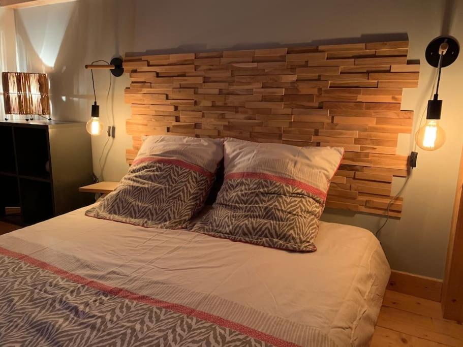 a bed with two pillows and a brick wall at Chaleureux studio plein sud en Tarentaise ! in Bozel