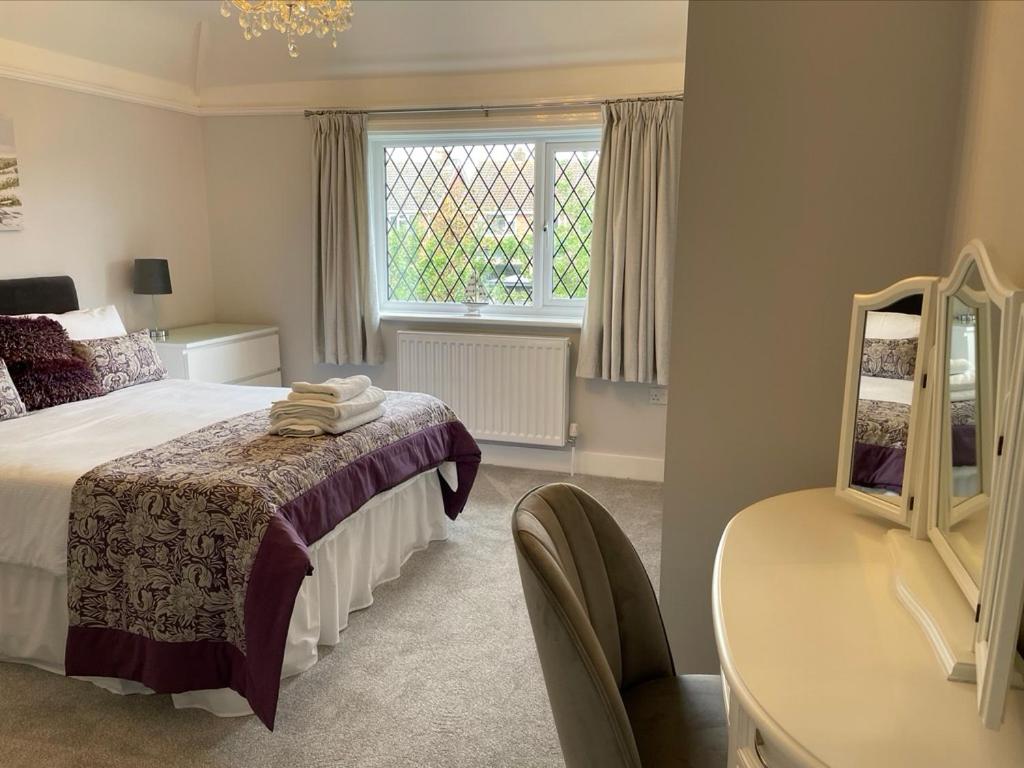 1 dormitorio con cama, mesa y espejo en Walton House en Frinton-on-Sea