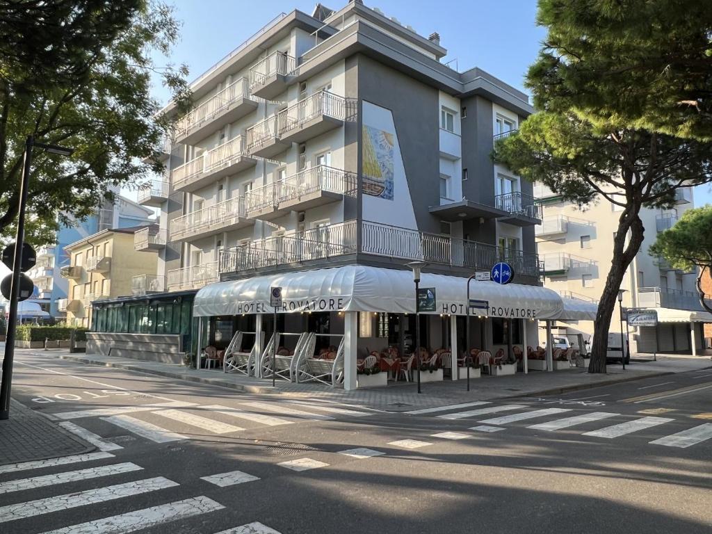 un edificio con mesas y sombrillas en una calle de la ciudad en Hotel Trovatore, en Lido di Jesolo