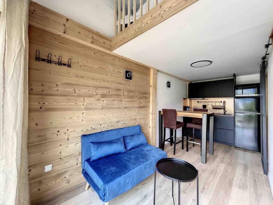 a living room with a blue couch and a kitchen at Petit loft chaleureux et cosy - vue montagne in Guillestre