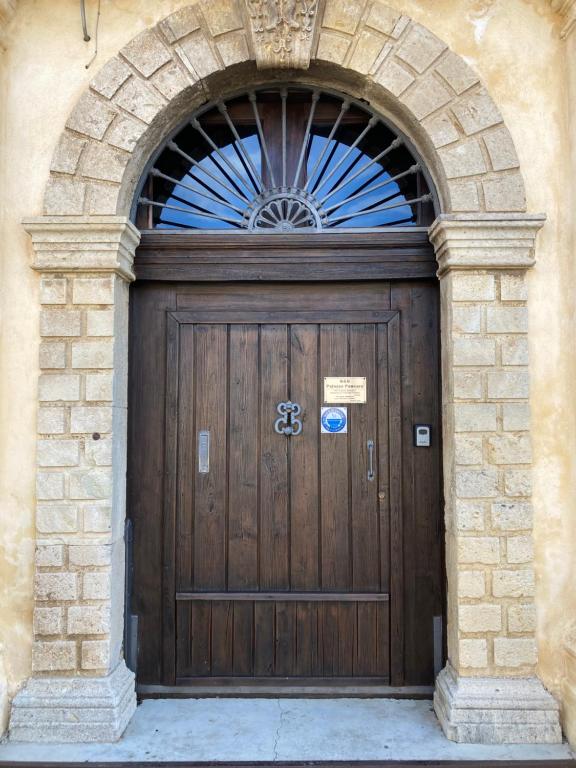 drewniane drzwi w kamiennym budynku z łukiem w obiekcie B&B Palazzo Pancaro w mieście Altomonte