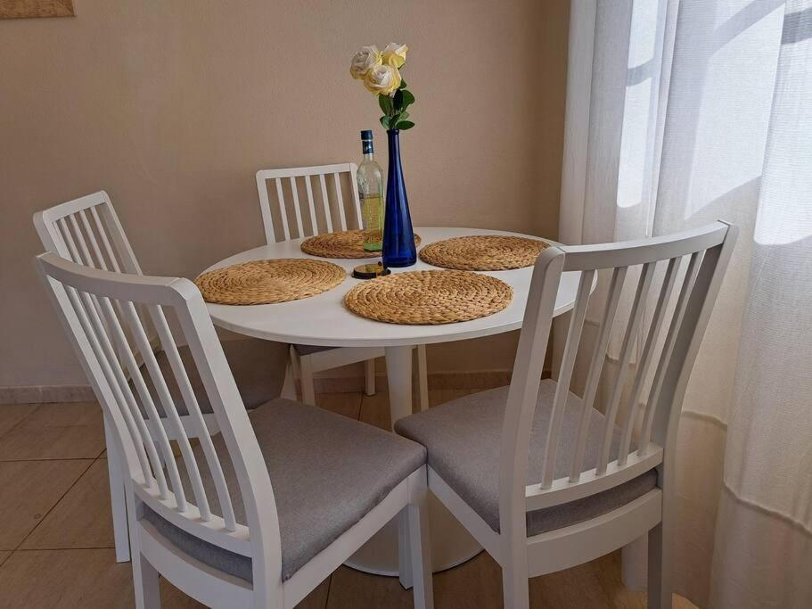 a white table with three chairs and a vase with flowers at Las Teresitas Apartment in San Andrés