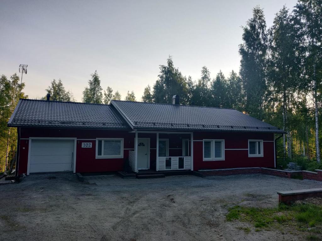 a red house with a garage in the woods at Mökki unelmia in Jyväskylä