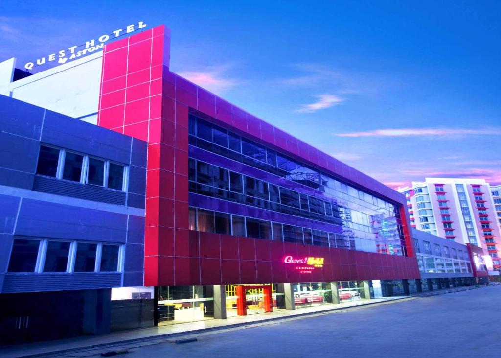 a red building with a sign on top of it at Quest Hotel Balikpapan by ASTON in Balikpapan