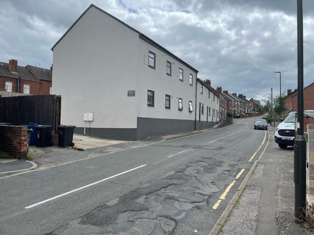 an empty street with a white building on the side at Middlecroft in Chesterfield