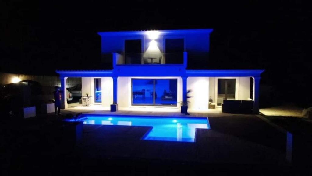 een blauw huis met een zwembad in de nacht bij SUITE 20m2 DANS VILLA PISCINE JACUZZI in Gattières