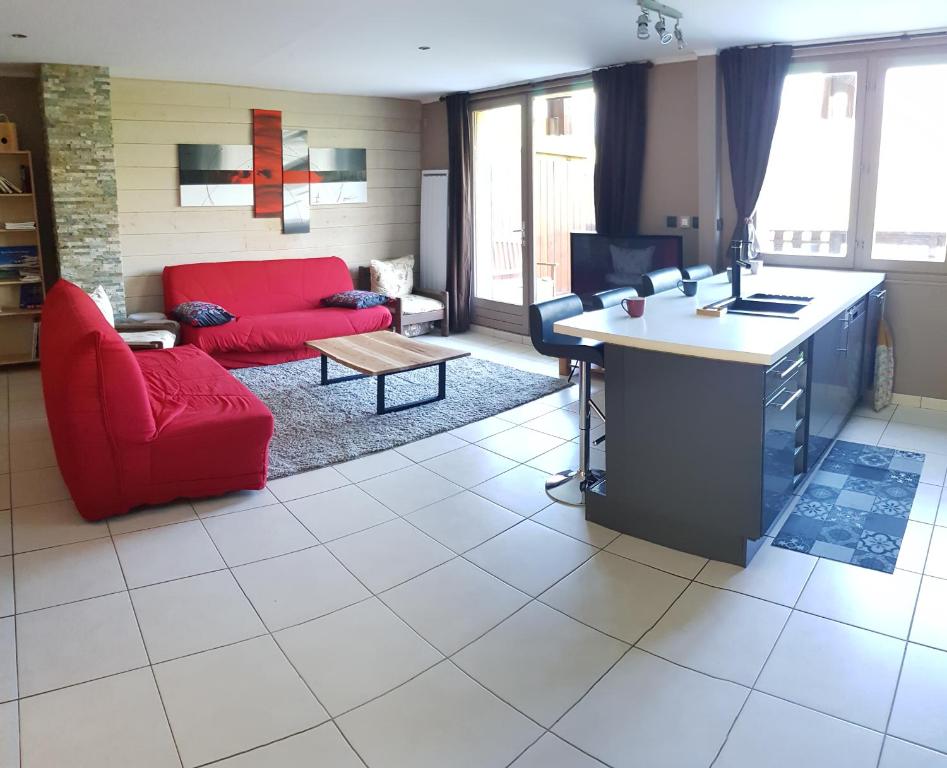 a living room with a red couch and a table at Les Balcons de l'Eterlou in Les Deux Alpes