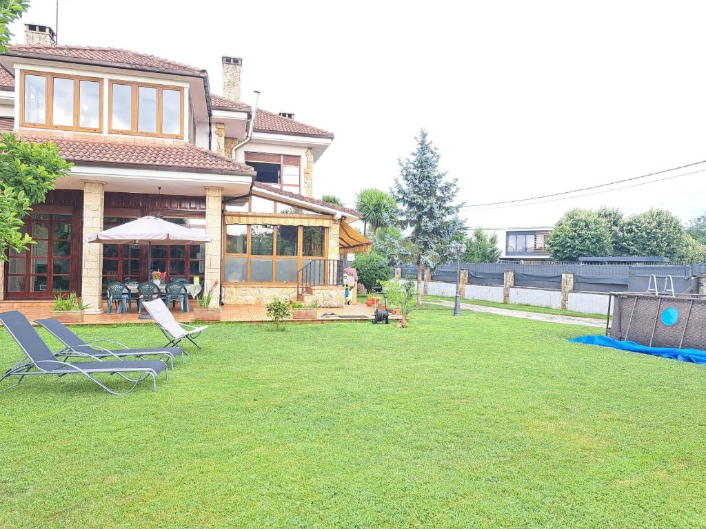 a yard with two lawn chairs and a house at Casa Chalet, Villa Elisa in Gijón