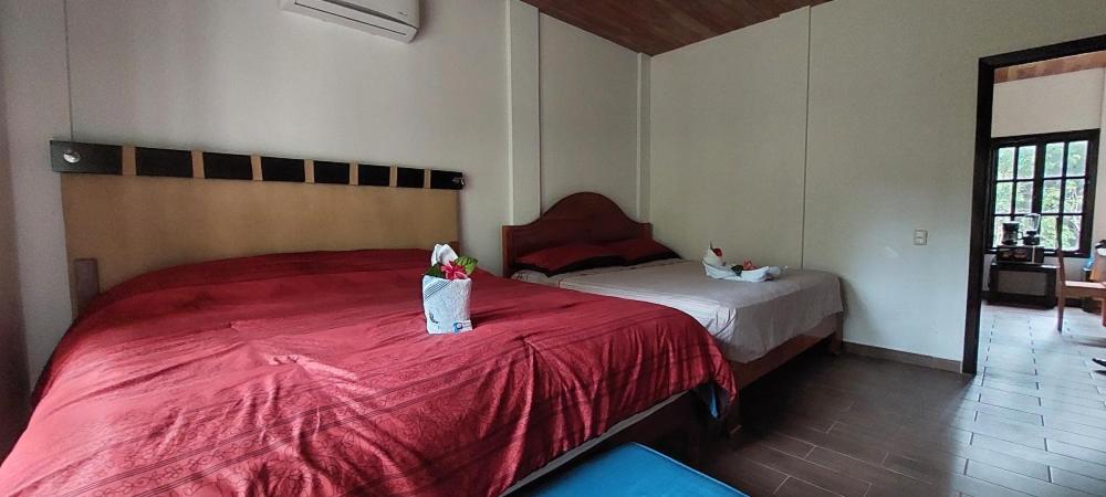 Schlafzimmer mit einem Bett mit einer roten Bettdecke in der Unterkunft Tu Casa en la Selva Lacandona in Champa