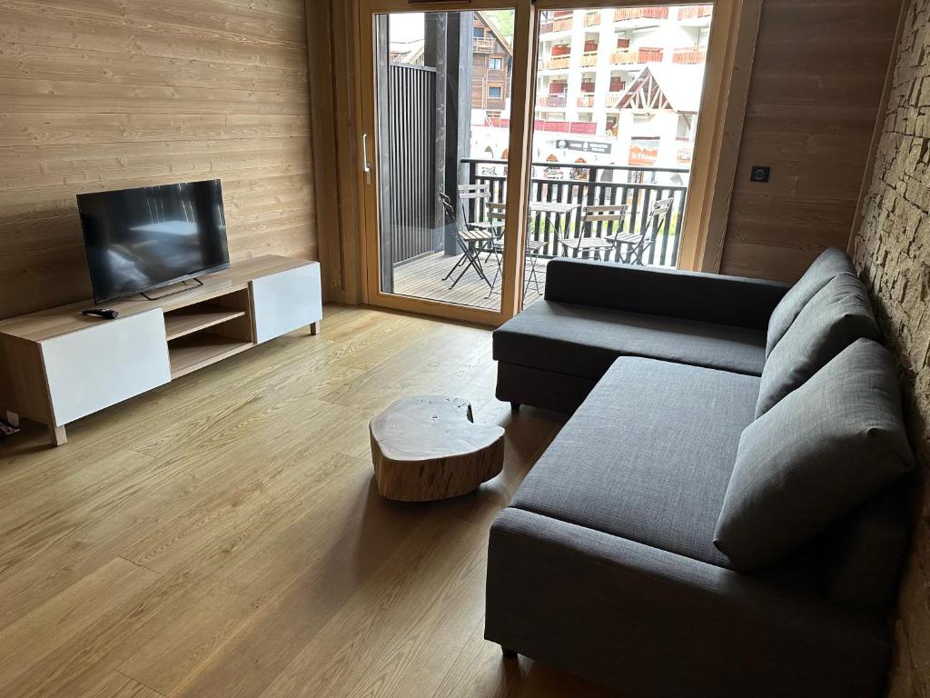 a living room with a couch and a television at Appartement de luxe, parking sous-terrain, centre-ville Auron in Auron