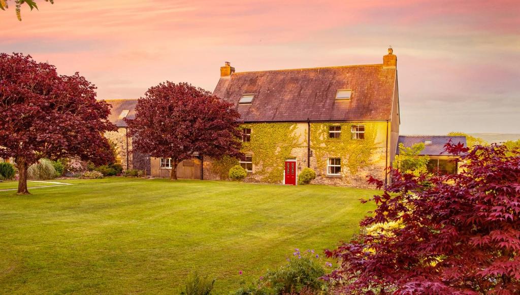 an old stone house with a green yard at Kidwelly Farmhouse in Kidwelly