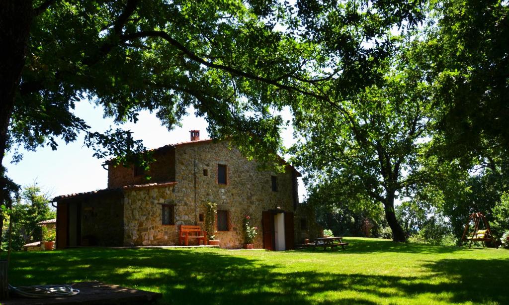 an old stone building in a field with a tree at Il Venaio in Massa Marittima