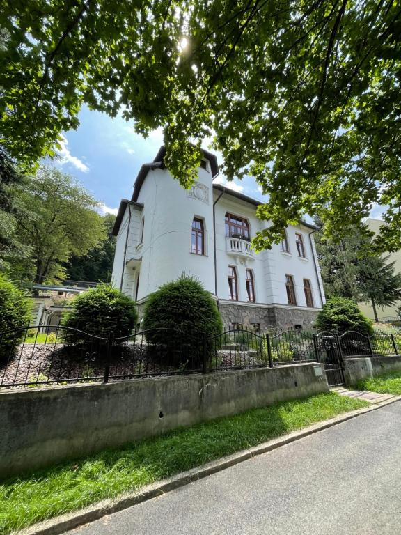 Podbrezová的住宿－Historická vila Dom hostí，前面有树木的白色大建筑