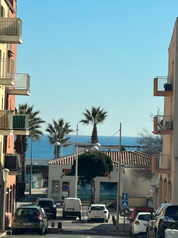 une rue avec des voitures garées dans une ville bordée de palmiers dans l'établissement L'Acropole, au Cap d'Agde