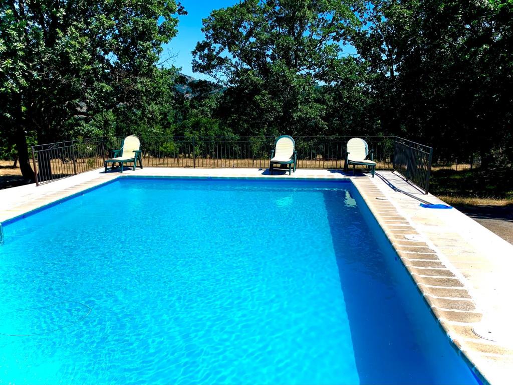 - une piscine bleue avec 2 chaises dans l'établissement Casa Rural Fuentecillas, à Becedas