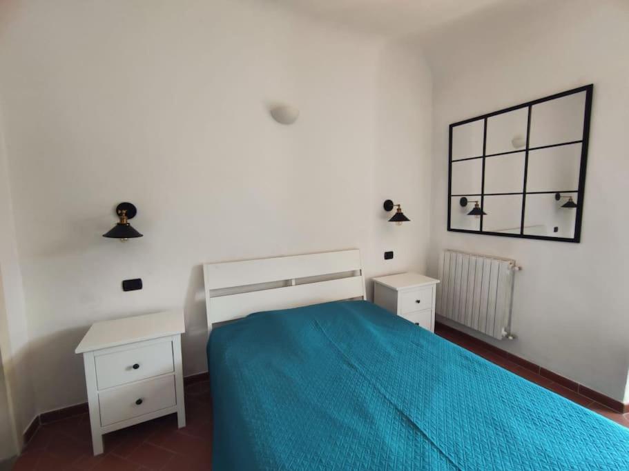 ein weißes Schlafzimmer mit einem blauen Bett und einem Spiegel in der Unterkunft Border House in Fiesole