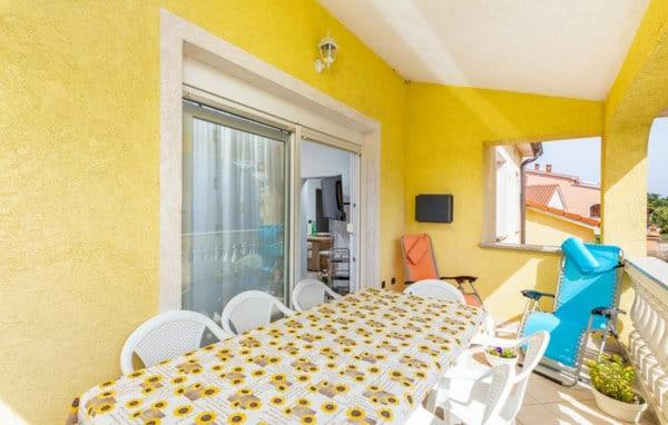 Habitación amarilla con balcón con mesa y sillas. en Apartment Jela en Fažana