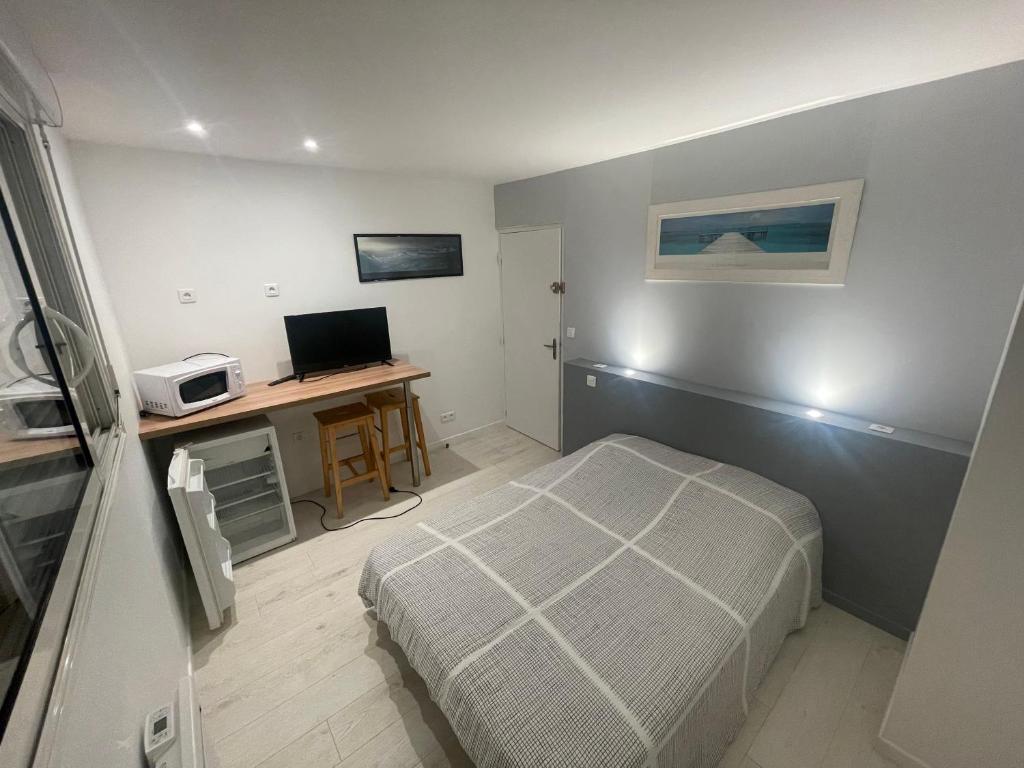 1 dormitorio con 1 cama y escritorio con ordenador en chambre etage fonctionnelle et independante, en Saucats