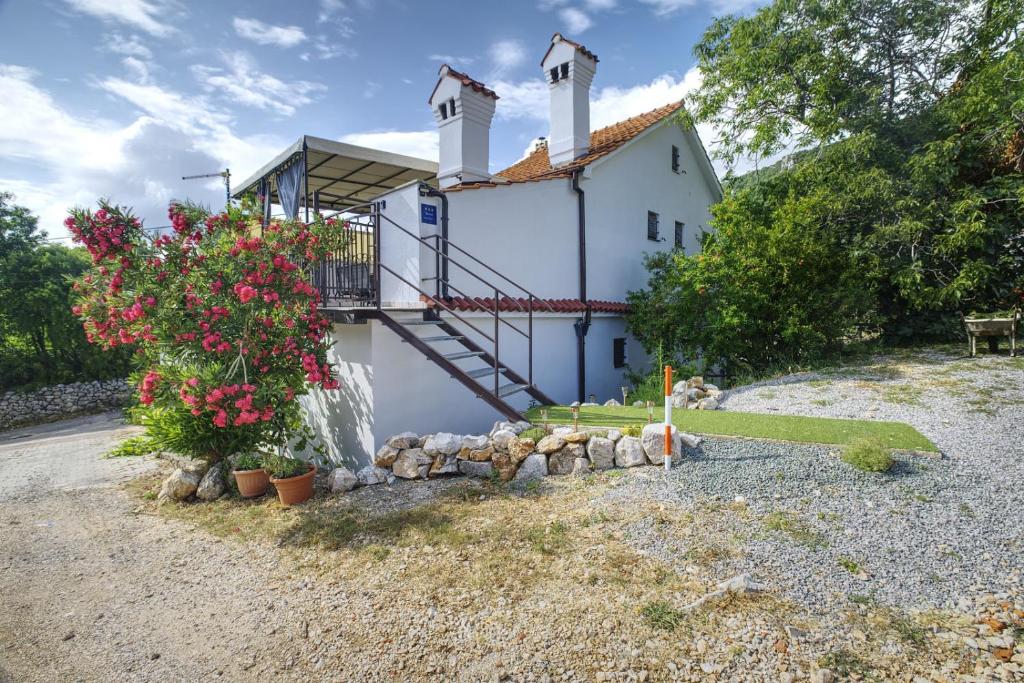 a house with a staircase and flowers in front of it at Apartman Tina in Grižane