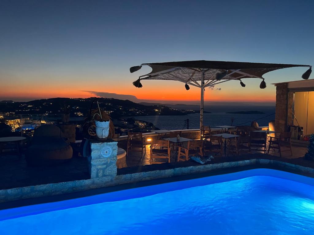 a swimming pool with an umbrella and a sunset at Chill Out Studio in Mikonos