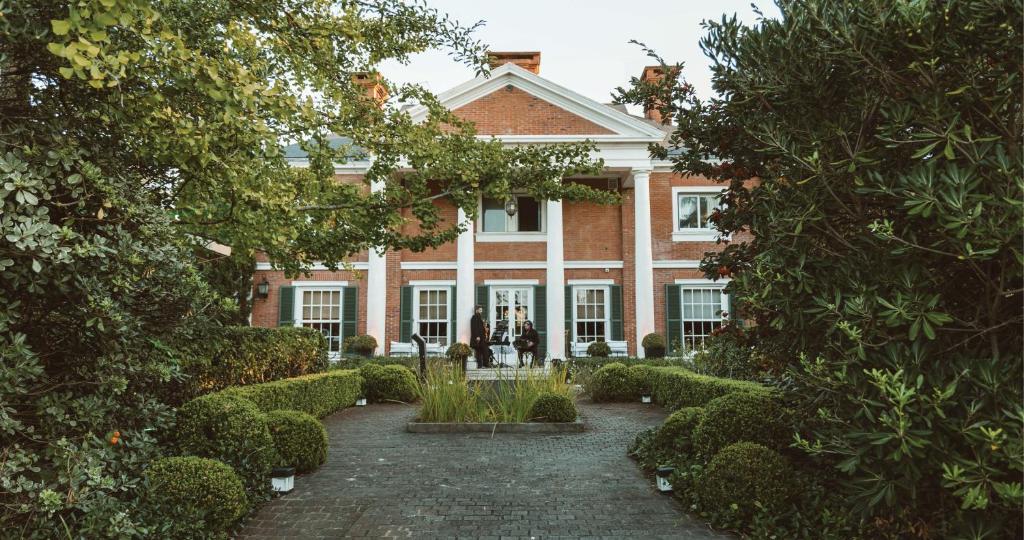 een groot bakstenen huis met bomen ervoor bij Le Bibló in Montevideo