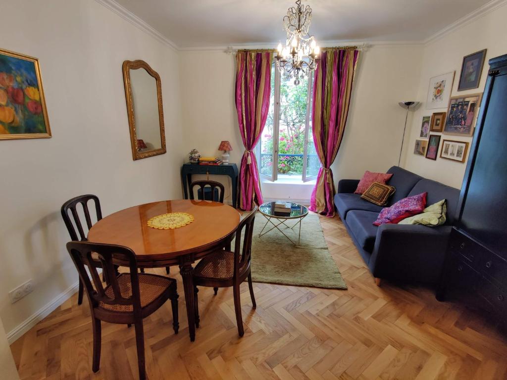 uma sala de estar com uma mesa e um sofá azul em Cozy apartment with a garden view in the 17th quartier em Paris