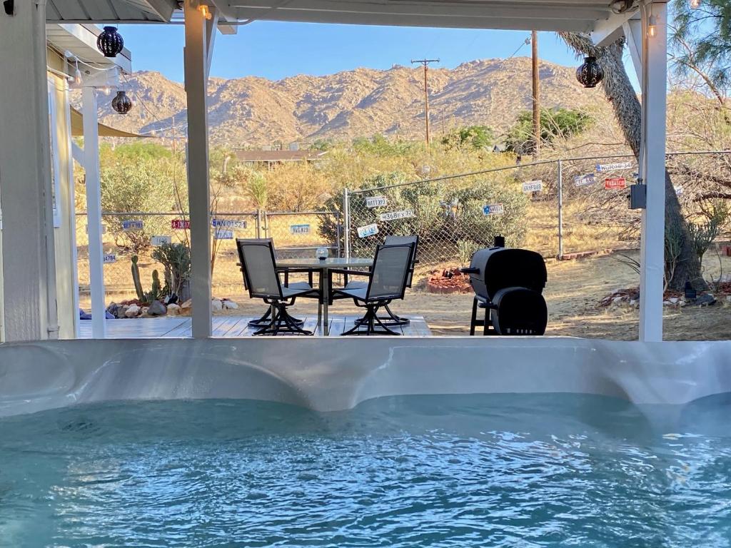 a patio with a table and chairs and a swimming pool at Float Pool, Hot Tub, Sauna, Firepit, BBQ, Telescope, Views, EV Chg, in Joshua Tree