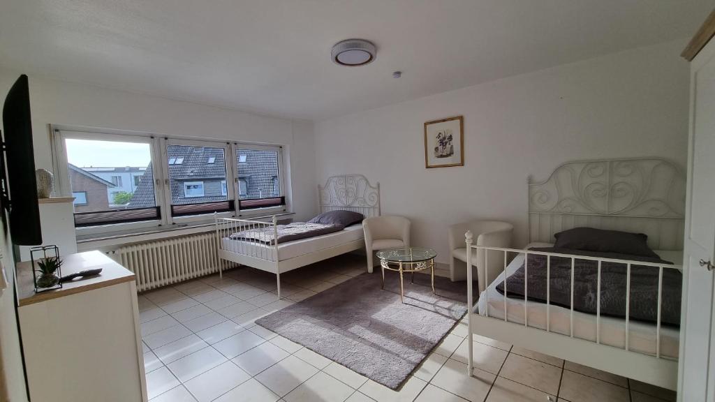a bedroom with two beds and a table and a window at Bocholt Apartment Ferienwohnung 3 in Bocholt