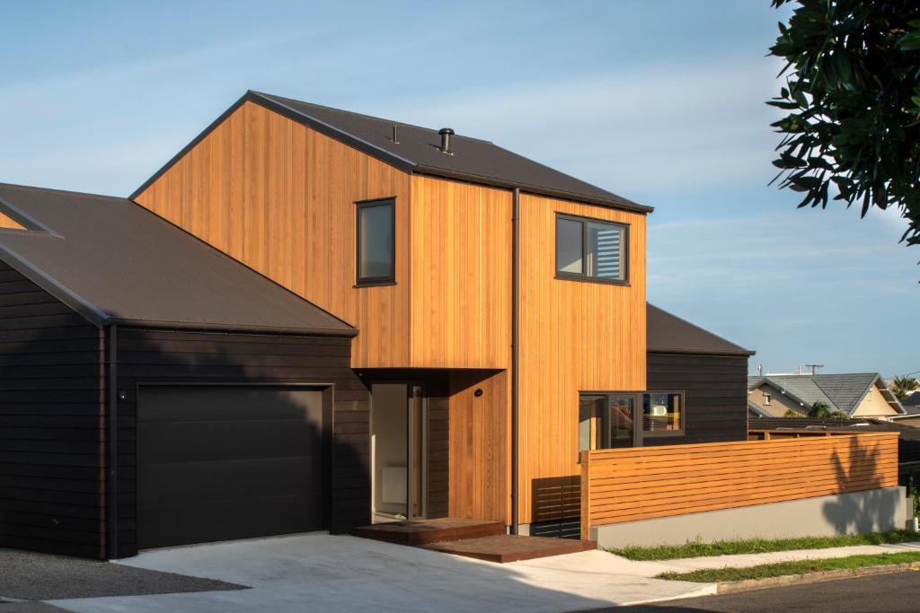 a house with a black roof and a garage at Twin Peaks Beach House - New Plymouth Holiday Home in New Plymouth