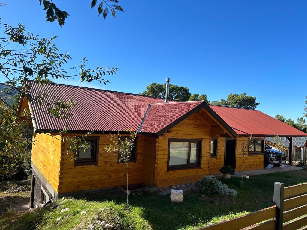 a small log cabin with a red roof at Casa y cabaña vista a las sierras in Villa Giardino