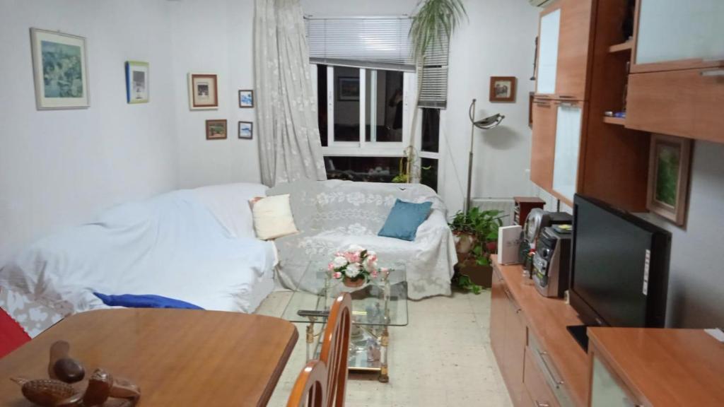 uma sala de estar com um sofá branco e uma janela em Carlos y Fernanda em Madri