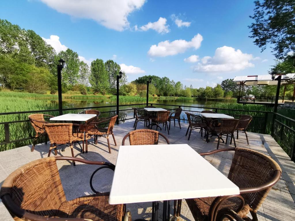 un patio avec des tables et des chaises à côté d'un lac dans l'établissement Szusz Szállás, à Debrecen